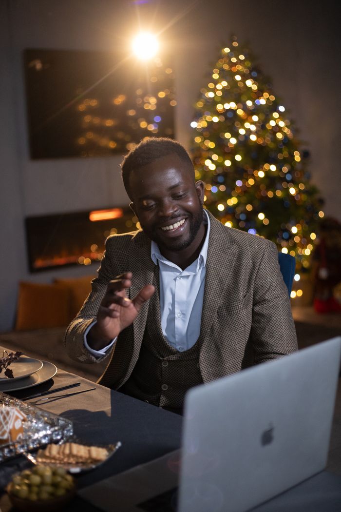 Professional man on a video call, celebrating Christmas indoors with decorations and a festive spirit.